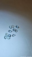 Cluster of multiple oval cut natural blue topaz gemstones on white background showing clarity and color.