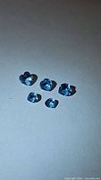 Five natural Swiss blue topaz gemstones arranged on a flat surface, showing clarity and color.