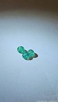 Three round green natural emerald gemstones shown on white background, displaying their color and size details.