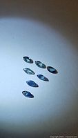 Seven marquis cut sapphires displaying multicolored hues under focused light