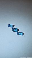 Three rectangular-cut natural Swiss blue topaz gemstones shown on a neutral background