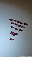 Multiple marquise cut natural untreated rubies spread out on a plain background.