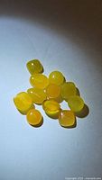 Group of natural yellow onyx mixed cabochon gemstones on a white background under direct light showing color and clarity.
