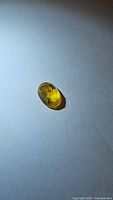 Top and angled views of a natural yellow sapphire gemstone 7x5mm with fancy rose cut facets, showing the yellow color and some internal characteristics.