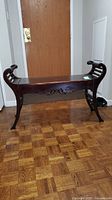 Full front view of vintage wooden piano bench with curved legs and carved detailing.