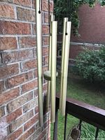 Close-up of the four metal tubular chimes hanging with central wooden striker outdoors.