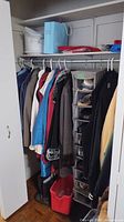 Closet view showing several hanging jackets in different colors and a vertical shoe organizer packed with multiple pairs of shoes.