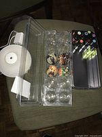 Lot contents shown on a chair, including white electric diffuser, metal tin with oils, and clear plastic tray holding four decorative eggs.