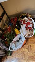 Photo showing bundles of assorted faux flowers including colorful blooms and greenery on the floor.