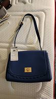 Blue Kate Spade purse with scalloped trim laid out flat showing front design and adjustable shoulder strap.