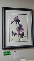 Full view of framed floral print mounted on wall with label and tag below