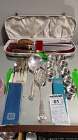 Overall view showing all items including carving set in case, napkin rings, serving spoons, flatware, and Birks napkin
