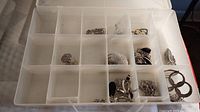 Clear plastic organizer with multiple compartments containing assorted sterling silver necklaces and earrings.