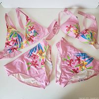 Photo of two pink floral patterned bikinis with triangle tops and matching bottoms showing the style and print details.