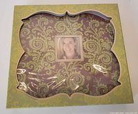 Closed Lotus Petal Starter scrapbook in box with lotus petal shaped cutout showing photo frame on book cover