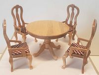 Front view of round dining table with four matching chairs in light wood and patterned cushions