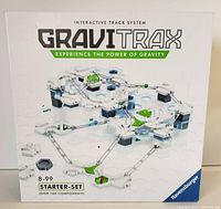 Front view of the GraviTrax Starter Set box showing the interactive track system with multiple components, hexagonal bases, and a marble running through the course.