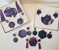 Full lot shot displaying multiple pairs of polymer clay jewelry including earrings and pins in shades of purple and blue, arranged on white boards.