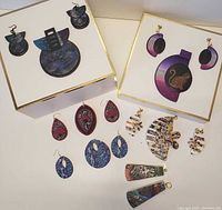 Photo showing an assortment of polymer clay jewelry including two pairs of large statement earrings with matching pendants, multiple pairs of smaller earrings in various colors and shapes, all arranged on a white surface.