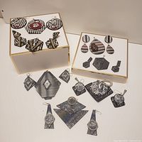 Overview of 15 polymer clay jewelry pieces including earrings and pendants in black, grey, white and silver tones with geometric patterns
