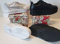 White and black Puma athletic shoes displayed on or near their boxes, soles shown showing tread pattern and overall shoe design