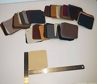 Photo showing spread-out leather sample swatches in multiple colors with two rulers for size reference.