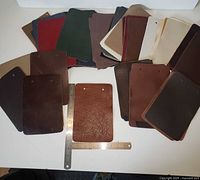 Array of leather samples spread on a table, showing variety of colors and thicknesses with a metal ruler for scale.