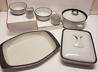 Overall view of all pieces arranged neatly showing variety of shapes and sizes including lidded pots, bowls, cups, and trays.