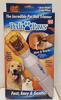 Front view of the product box showing the Pedi Paws nail trimmer with features outlined including quiet motor, traps filings, battery powered, and gentle nail trimming for pets.
