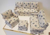 Front view of the four dollhouse furniture pieces on a white surface, showing floral upholstery.