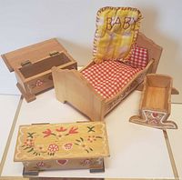 Four vintage dollhouse baby room furniture pieces including bed, cradle, chest, and toy box with hand-painted folk art decorations and gingham bedding