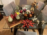 overview of lot on glass table showing pears, orbs, figurines, tray and silver items