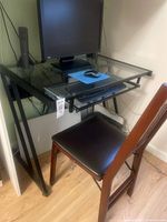 Desk and chair set front view showing glass top, metal frame, wooden chair