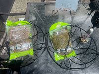 Two black metal hanging baskets with bags of preserved moss on patio table