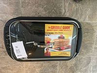 Grill with glass lid, cookbook inside on top of griddle plate