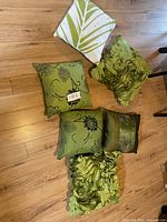 Six green decorative pillows laid out showing fronts