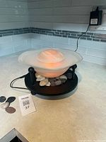 Full view of fountain on countertop with orange LED glow, adapter plugged in