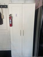 front view of white wardrobe cabinet with fire extinguisher mounted