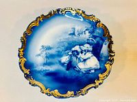 Full view of the antique Royal Bayreuth porcelain plate showing the blue and white center scene and ornate gold rim.
