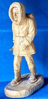 Front view of the wood carving sculpture showing person in hooded parka and snowshoes.