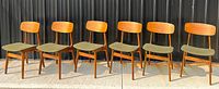 Six teak dining chairs in a row outdoors