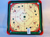Full view of the multi-game board showing the Carrom and Checkers layout on a square wooden frame with rounded red edges.