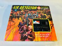 Box artwork of vintage 1960s Mattel Lie Detector game showing TV studio scene and visible lie detector unit