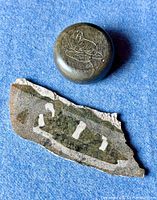Two Indigenous Inuit soapstone carvings placed on blue surface, one round with seal engraving and one irregular shaped with abstract animal carving.