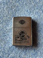 Front view of silver Zippo lighter showing black engraving of Harley Davidson logo, Sturgis South Dakota 1990, 50th anniversary and Mt. Rushmore themed artwork