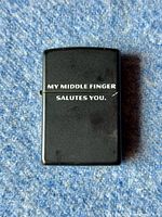 Front view of black Zippo lighter showing text: 'MY MIDDLE FINGER SALUTES YOU'