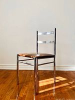 Front and angled views of a 1970s Mid-Century Modern chair showing the chrome tubular metal frame and amber vinyl padded seat on hardwood floor.