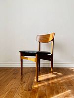 Side angled view of teak chair showcasing curved backrest and wood frame condition.