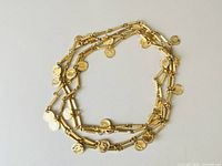 Photo showing gold tone multi-layer coin necklace laid flat in a circular shape against white background.