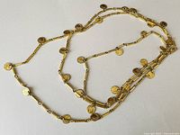 Full view of the vintage gold tone multi-layer coin statement necklace laid out flat to show the full length and arrangement of coin charms.